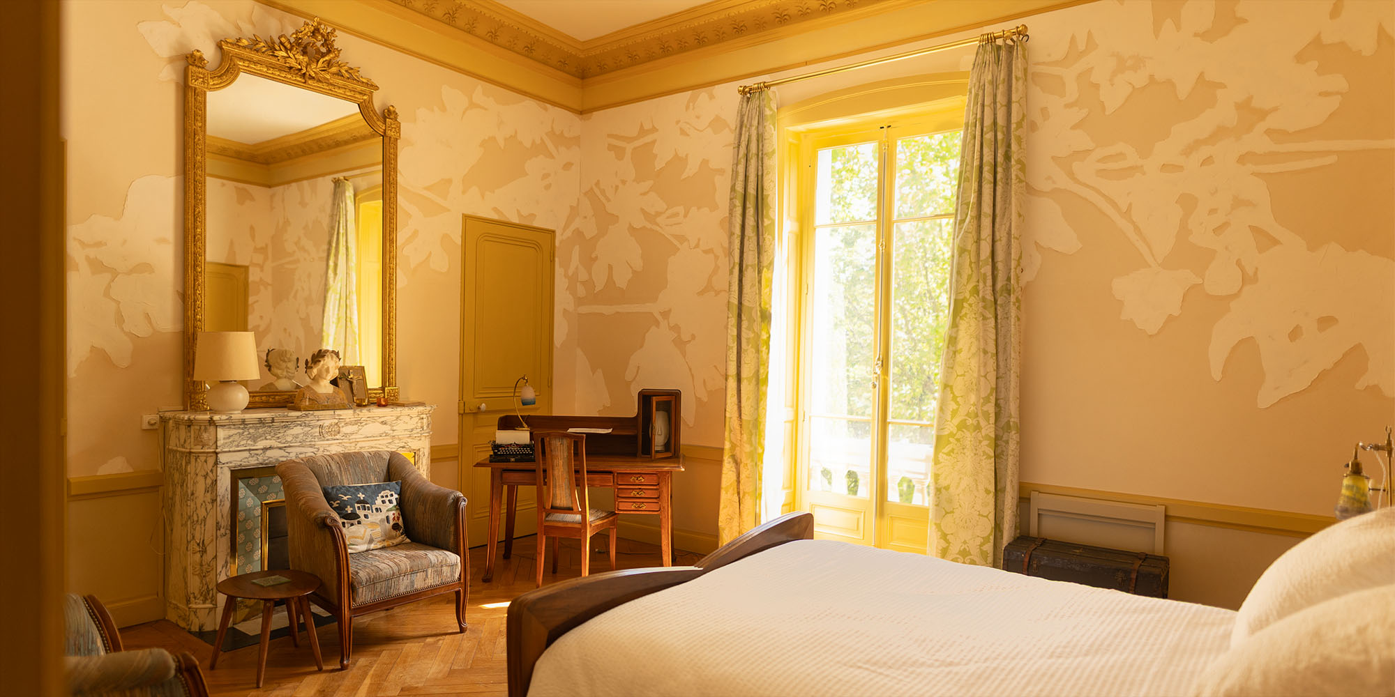Vue d'ensemble de la chambre avec son mobilioer Art Nouveau et la lumière douce de la grande fenêtre.